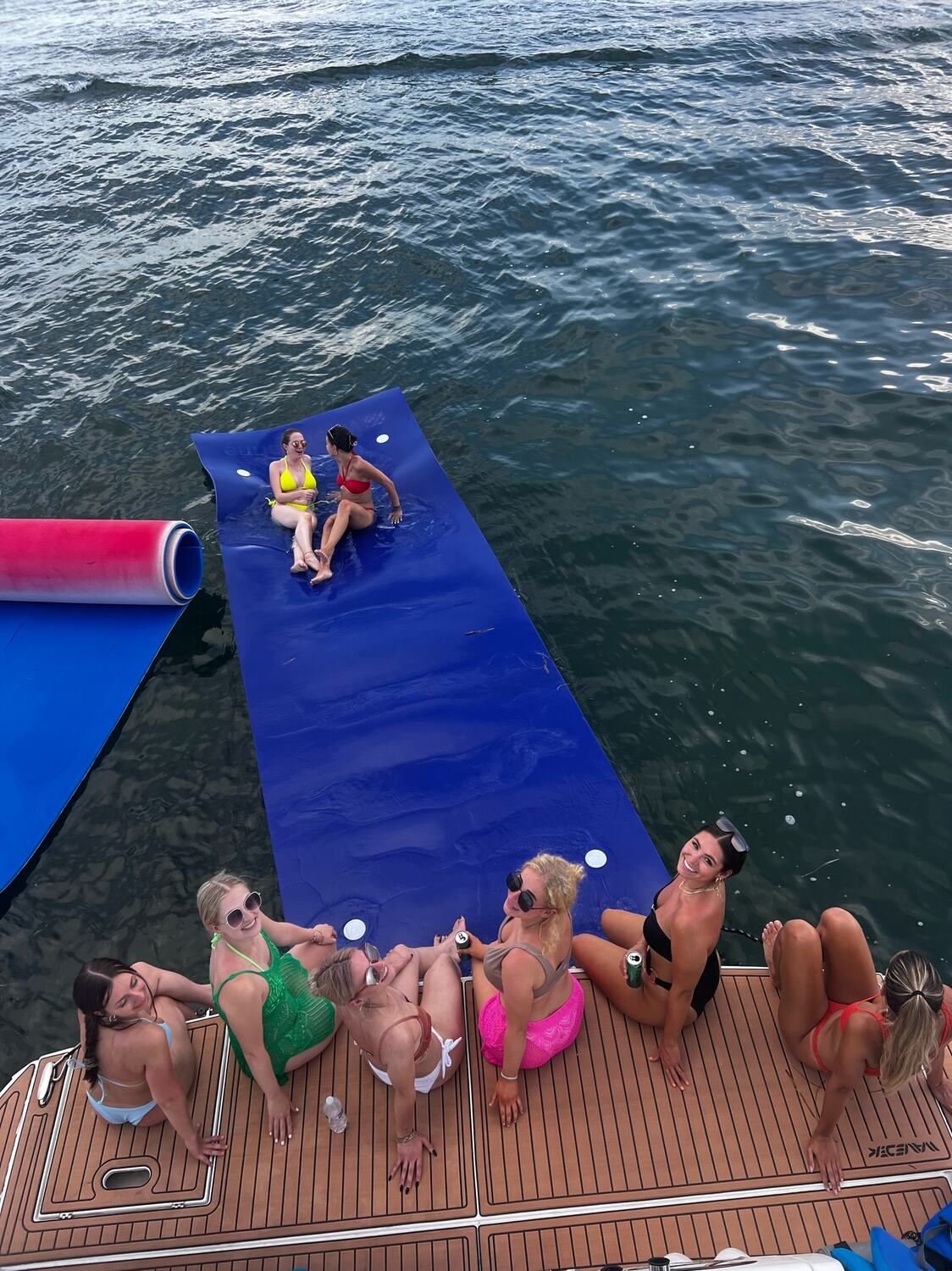 Guests relaxing on a floating water mat off the swim platform