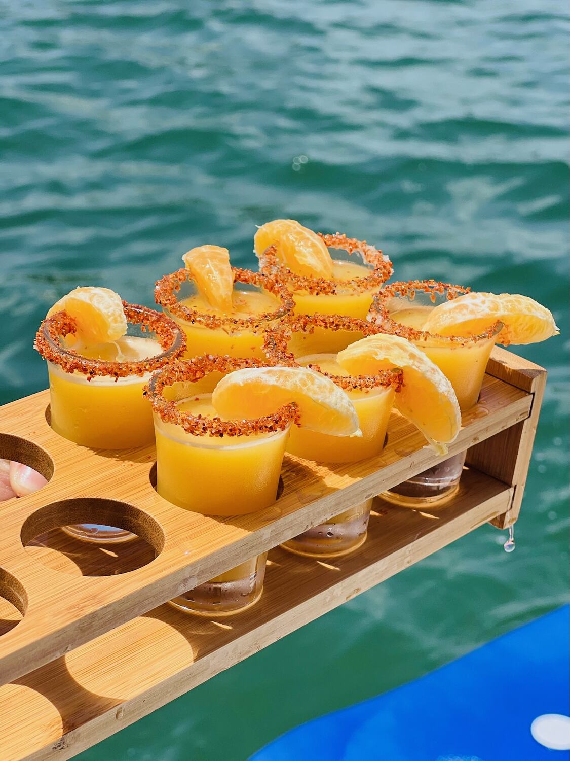 Tray of mimosa shots with orange slices over the water