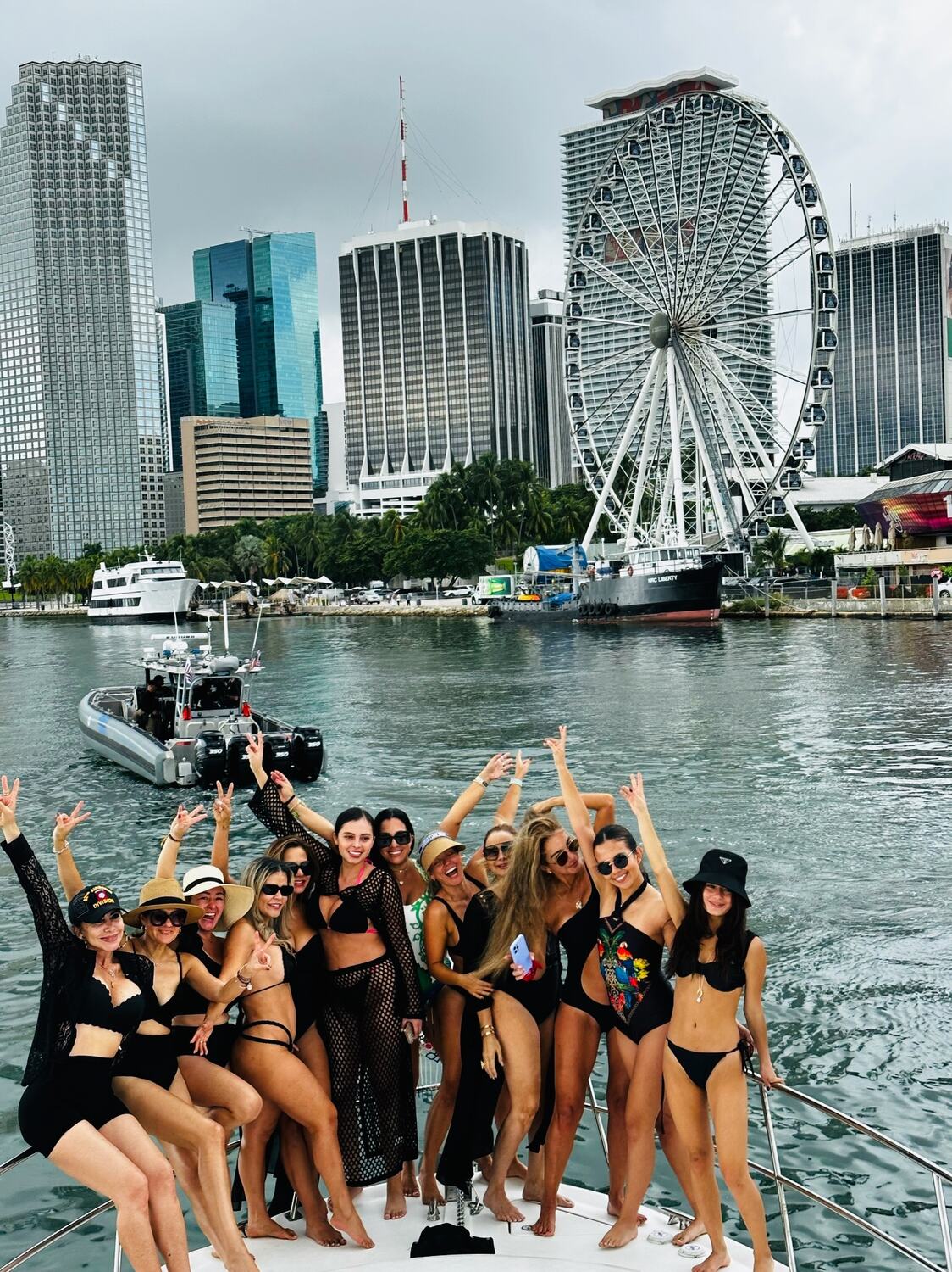 A bachelorette group cheering on the bow in front of the Miami skyline